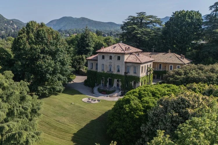 The villa and its lawn, surrounded by trees with hills behind